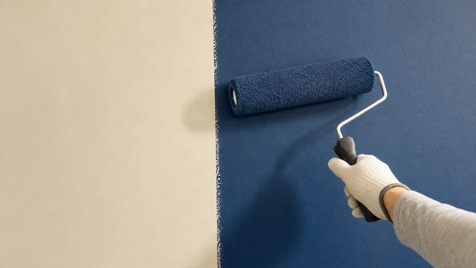 Illustrative view of a wall being painted with a roller.